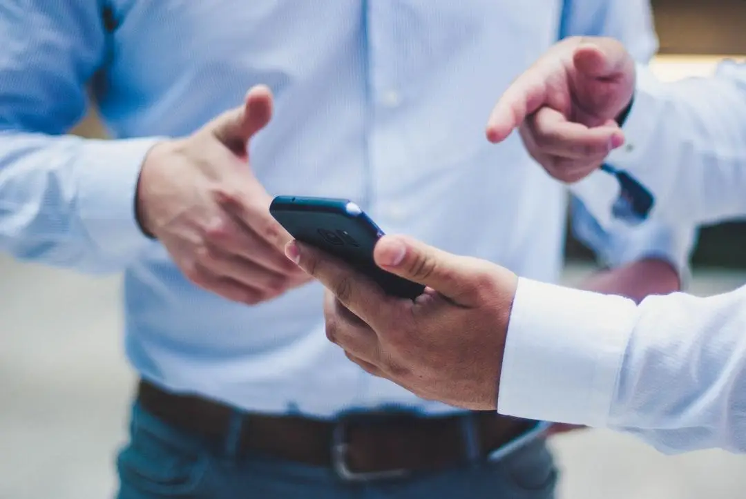 two people pointing at a mobile phone